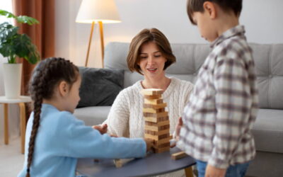 Une mère et ses deux enfants jouent à la tour Jenga en bois dans un salon lumineux, illustrant la garde alternée et la résidence des enfants à Lyon.