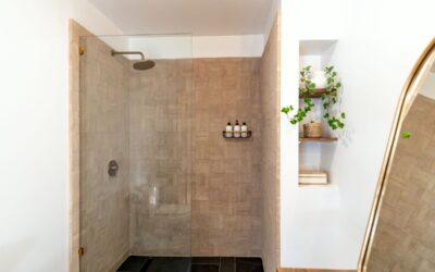 Douche à l'italienne avec paroi en verre, carrelage beige, étagère et miroir